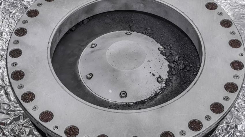 A view of the outside of the OSIRIS-REx sample collector. Sample material from asteroid Bennu can be seen on the middle right. Scientists have found evidence of both carbon and water in initial analysis of this material. The bulk of the sample is located inside.